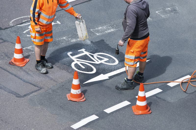 Road Workers in Orange Uniforms Renovate Road Markings Stock Image