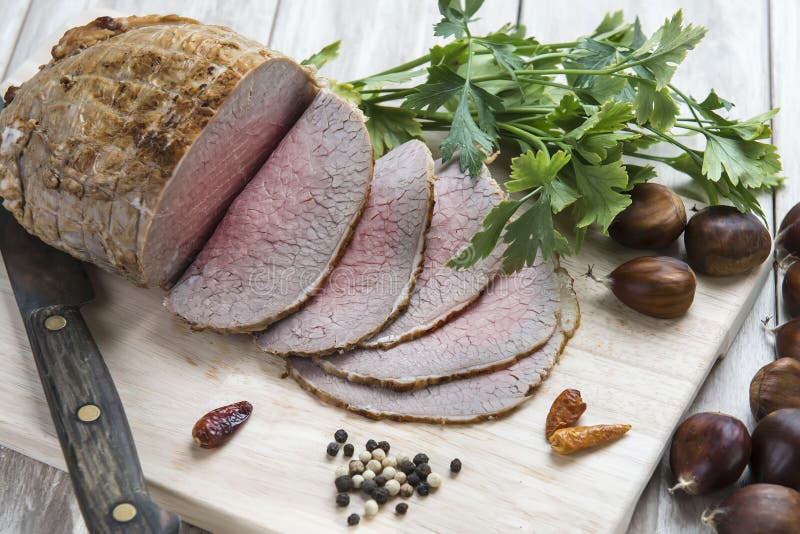 Sliced roast beef with some ingredients on the table of the kitchen