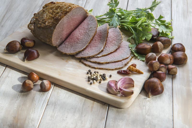 Sliced roast beef with some ingredients on the table of the kitchen