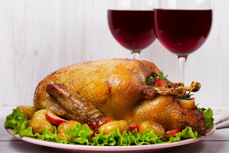 Roast duck with potato, apples, salad, thyme and rosemary. Two glasses of red wine