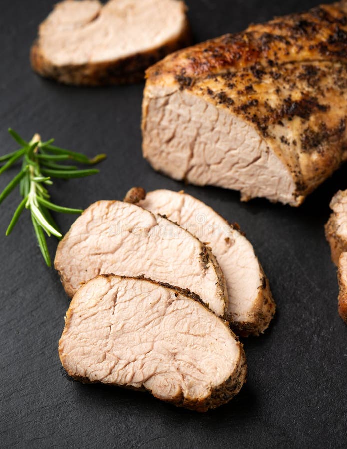 Roast Pork Tenderloin with Herbs on Rustic Stone Board Stock Photo
