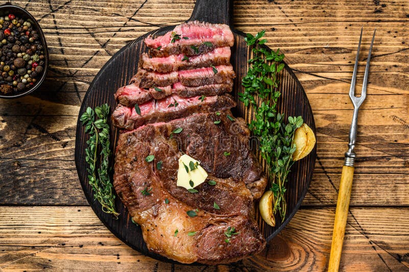 Roast Rib Eye Beef Meat Steak on a Cutting Board. Wooden Background. Top View Stock Image - Image of roll, sirloin: 208622419