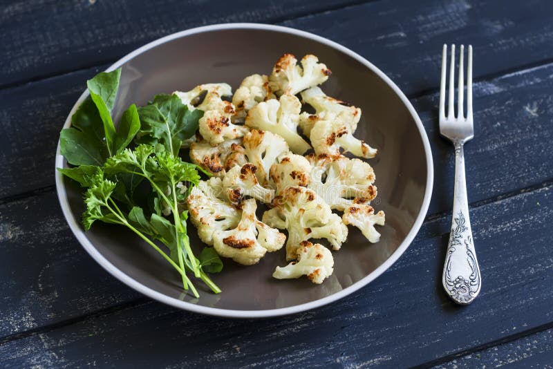 Roasted cauliflower and fresh green salad on a brown plate stock image Roasted cauliflower and fresh green salad on a brown plate stock image