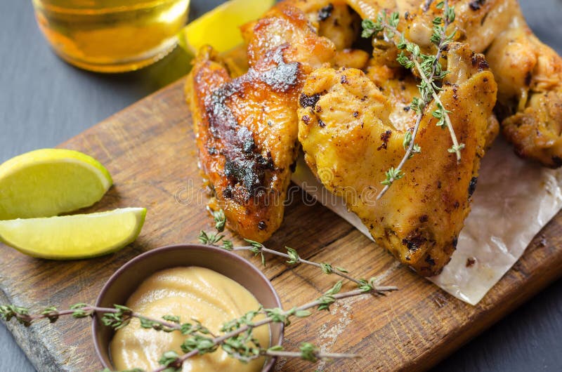 Roasted Chicken Wings with Mustard and Lime, Beer on Background. Stock