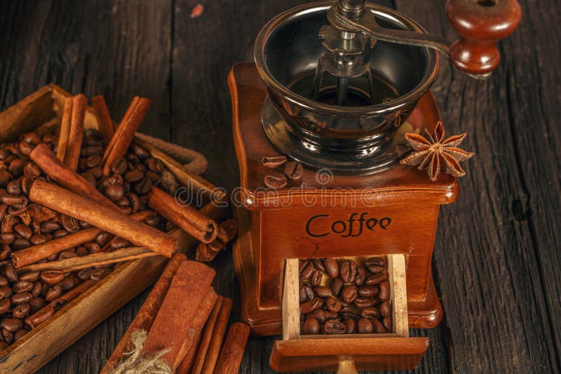Roasted coffee bean with cinnamon and coffee grinder on wooden background. Coffee beans with cinnamon chopsticks on a black wooden stock image Roasted coffee bean with cinnamon and coffee grinder on wooden background. Coffee beans with cinnamon chopsticks on a black wooden stock image