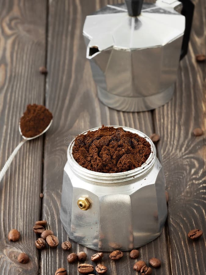 Roasted coffee beans in a glass jar, scattered on a wooden brown table. Hand mill and coffee pot la moka in the background. stock photo Roasted coffee beans in a glass jar, scattered on a wooden brown table. Hand mill and coffee pot la moka in the background. stock photo