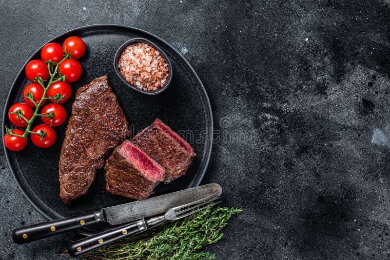 Roasted Cut Denver Beef Meat Steak on a Plate with Thyme. Black