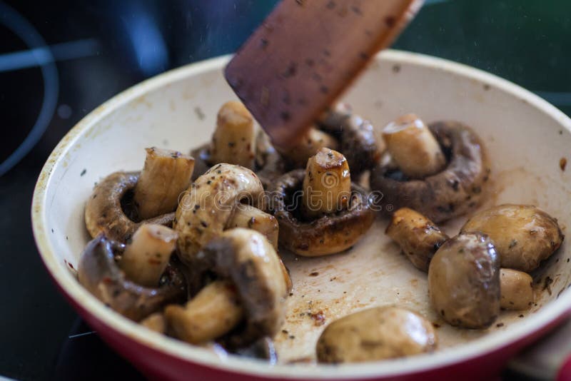Roasted field mushrooms, champignons being cooked in frying pan.