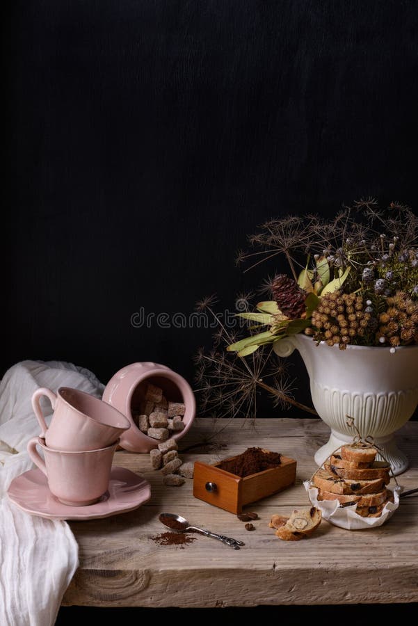 Roasted ground coffee in a wooden box with pink porcelain cups and cookies. Vintage still life on wooden table and copy space.