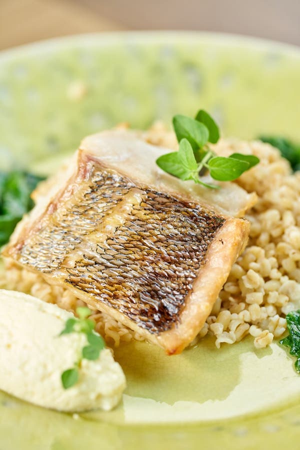 Roasted Pike perch with spelt and Polish sauce. Dish decorated with a spinach. Restaurant menu stock photos