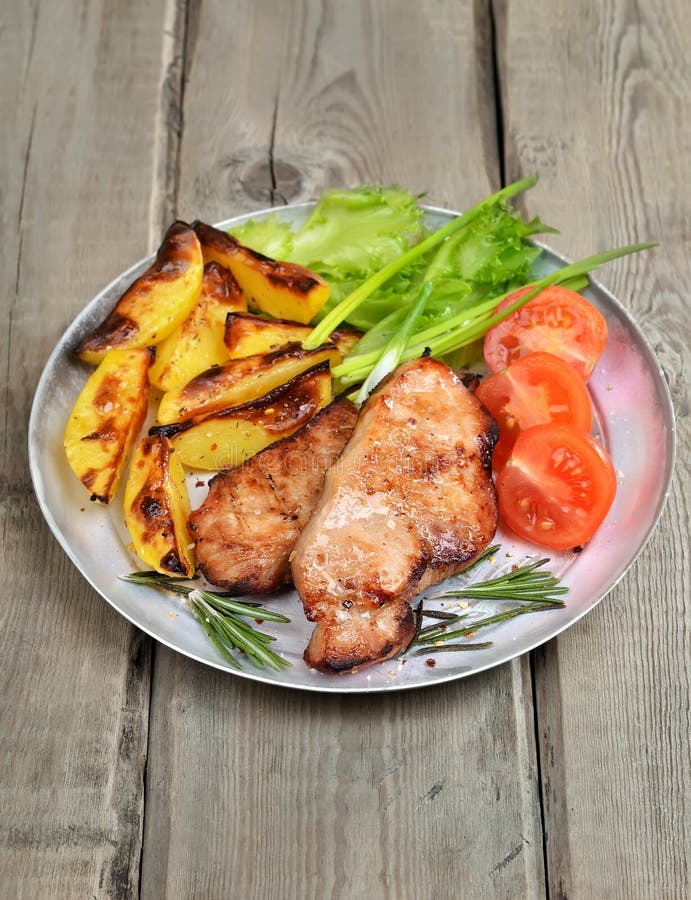 Roasted Pork Chop with Vegetables on Rustic Table Stock Photo - Image