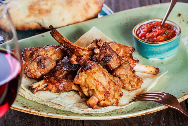 Roasted rabbit with herbs, tomato sauce and glass of wine on a plate. Hot Meat Dishes.