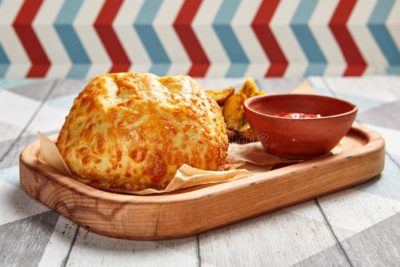 Roasted round cheese loaf and fried potatoes. Restaurant dish portion. Fast food serving with tomato sauce on wooden tray side view. Cafe quick meal close up stock image Roasted round cheese loaf and fried potatoes. Restaurant dish portion. Fast food serving with tomato sauce on wooden tray side view. Cafe quick meal close up stock image
