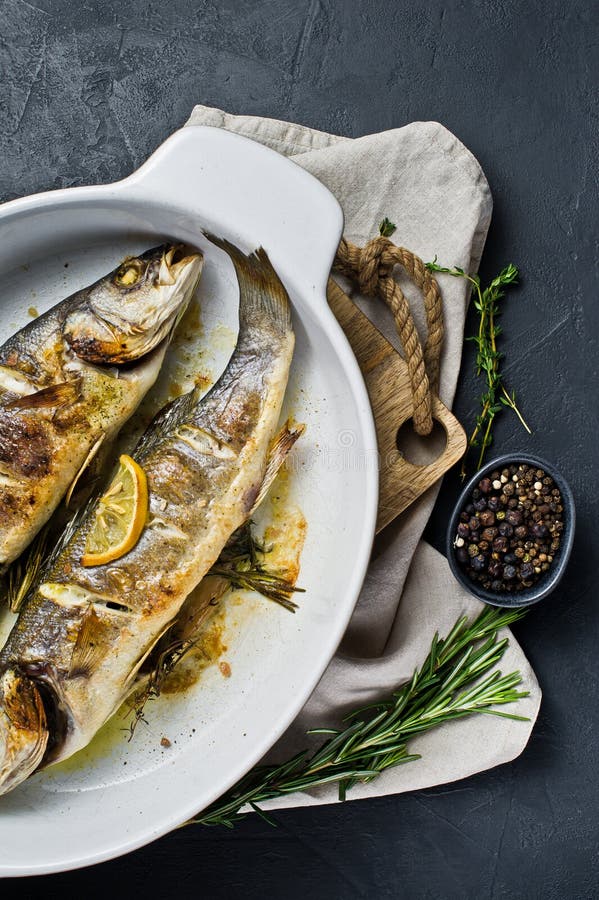Roasted Sea Bass in a Baking Dish. Black Background, Top View, Space