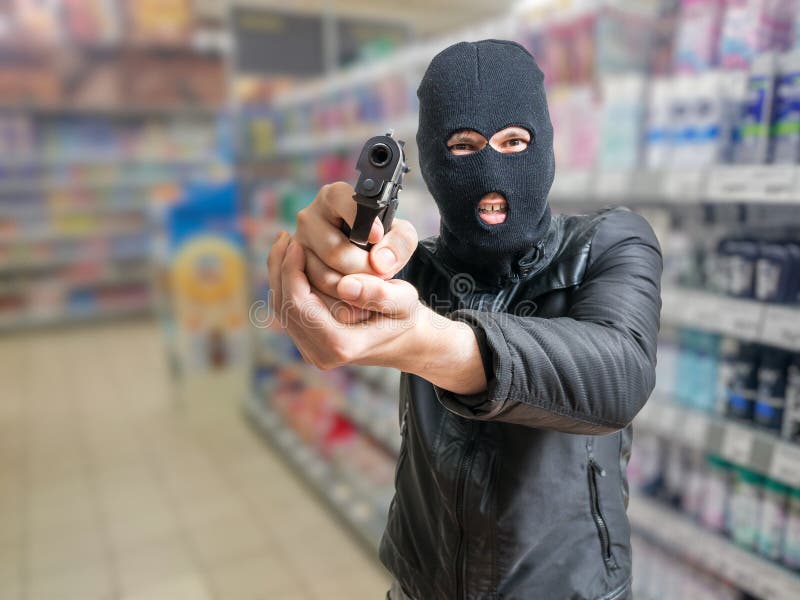 Robbery in store. Robber is aiming and threatening with gun in shop