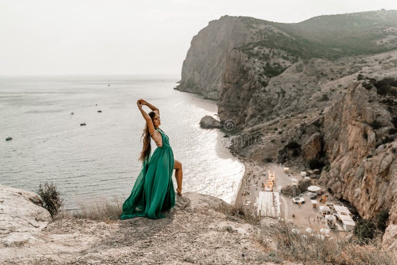 Robe verte pour femme sea trevel. vue latérale une femme heureuse aux cheveux longs en robe de menthe longue posant sur une plage image libre de droits