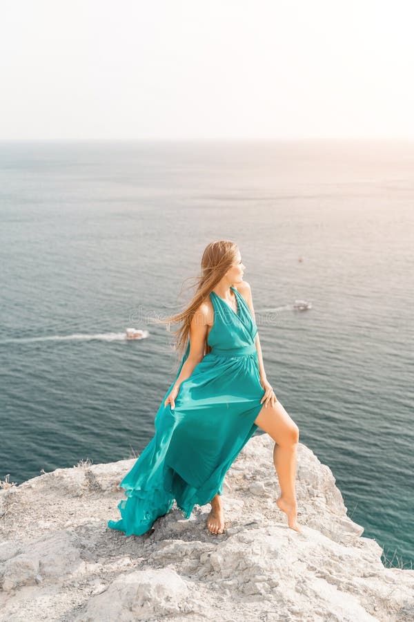Robe verte pour femme sea trevel. vue latérale une femme heureuse avec des cheveux longs en robe de menthe longue posant sur une p image stock