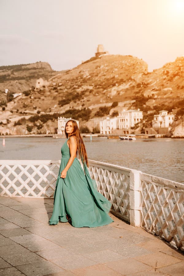 Robe verte pour femme sea trevel. vue latérale une femme heureuse avec des cheveux longs en robe de menthe longue posant sur une p photographie stock