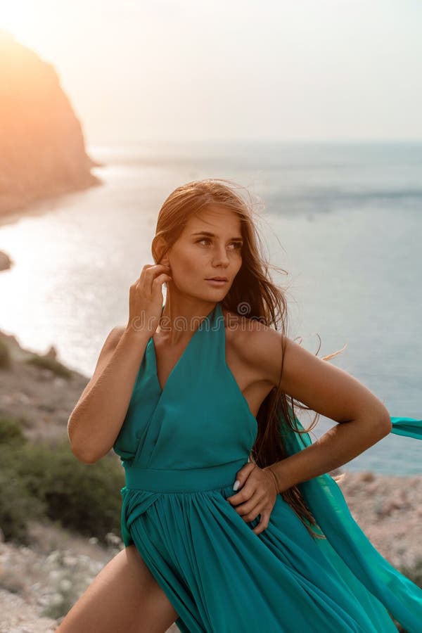 Robe verte pour femme sea trevel. vue latérale une femme heureuse avec des cheveux longs en robe de menthe longue posant sur une p photo libre de droits