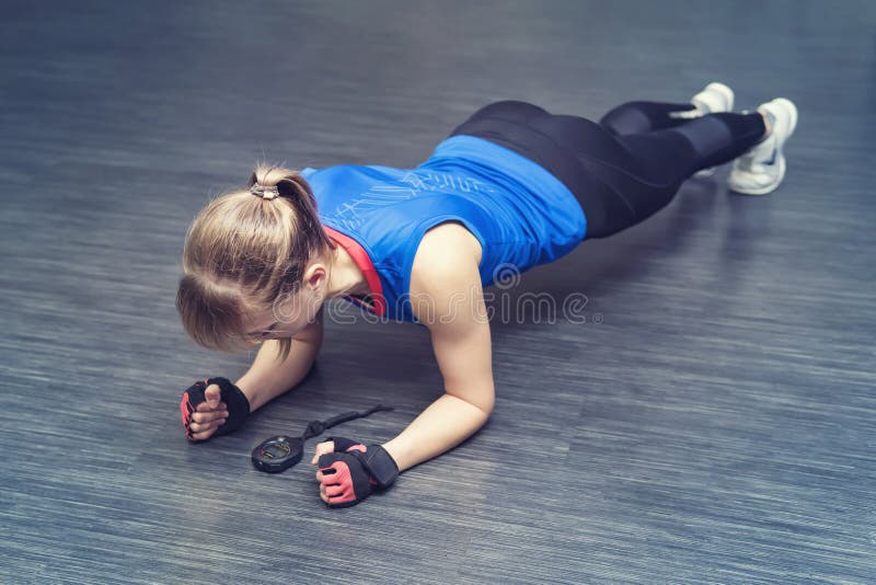 robić ćwiczeniu pcha robić kobiety Silny żeński robi crossfit trening blondynka stojaki na jej łokciach i spojrzenia przy stopwat zdjęcia royalty free robić ćwiczeniu pcha robić kobiety Silny żeński robi crossfit trening blondynka stojaki na jej łokciach i spojrzenia przy stopwat zdjęcia royalty free