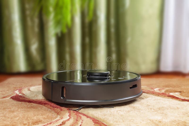 The robot vacuum cleaner in the room cleans the carpet stock photos The robot vacuum cleaner in the room cleans the carpet stock photos