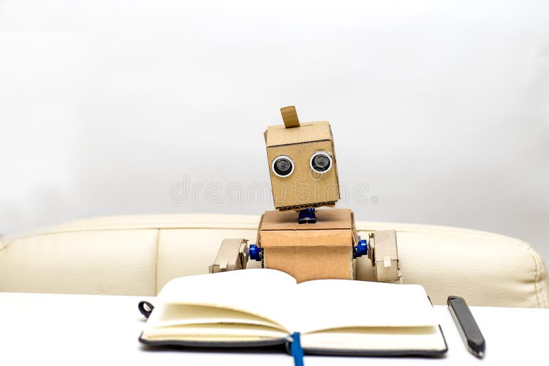 Roboten sitter på en tabell på en ljus bakgrund, arkivfoto Roboten sitter på en tabell på en ljus bakgrund, arkivfoto
