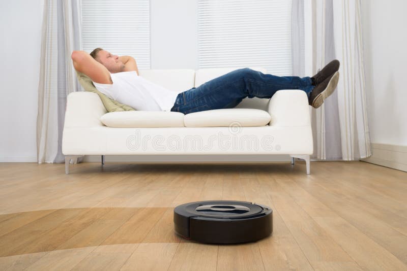 Robotic vacuum cleaner in front of man relaxing stock images Robotic vacuum cleaner in front of man relaxing stock images