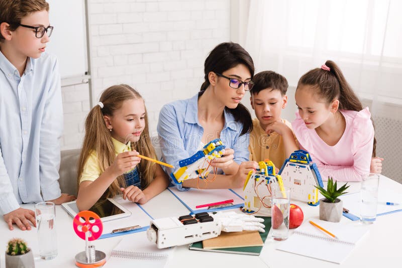 Robotics class. Teacher helping childern making diy robots royalty free stock images