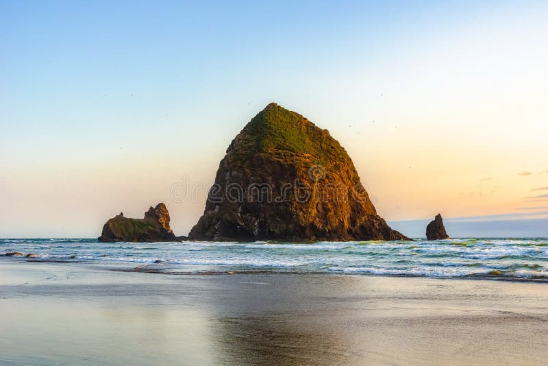 Roca hermosa del pajar, señal natural famosa de la Costa del Pacífico, en la puesta del sol, playa del cañón, costa de Oregon fotos de archivo Roca hermosa del pajar, señal natural famosa de la Costa del Pacífico, en la puesta del sol, playa del cañón, costa de Oregon fotos de archivo