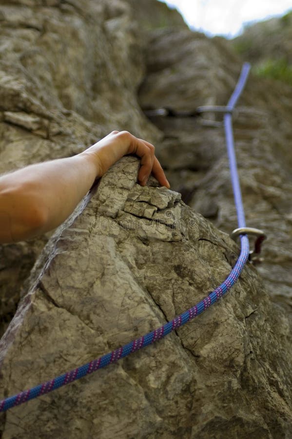 A rock climber's hand on rock. Focus on hand, rope and carabineer. A rock climber's hand on rock. Focus on hand, rope and carabineer.