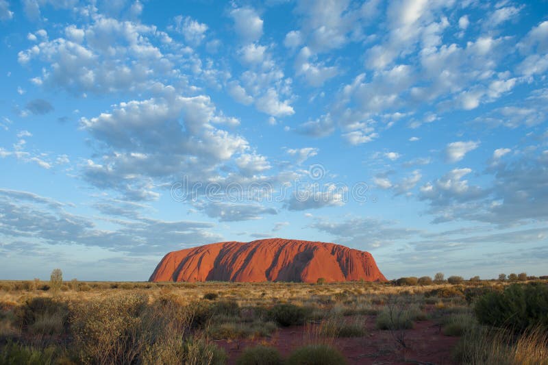 Ayers Rock, Uluru; a brilhar ao sol da manhã, céu azul com pequenas nuvens foto de stock