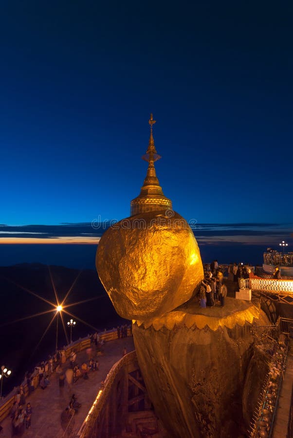 Rocha Dourada ao crepúsculo com pessoas em oração, Pagode KyaiKhtiyo fotografia de stock