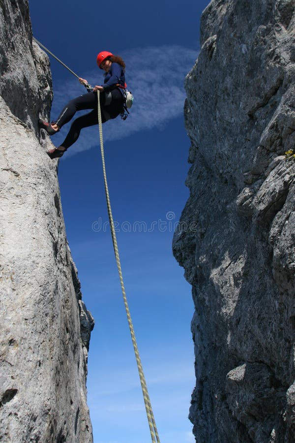 Frau mit Helm klettern die Felsen.