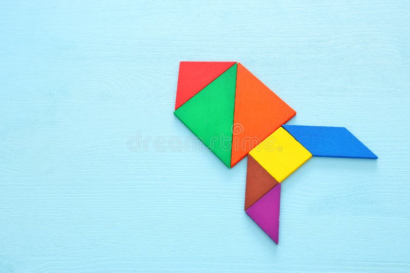 Rocket made from tangram puzzle on blue pastel wooden background. stock photo