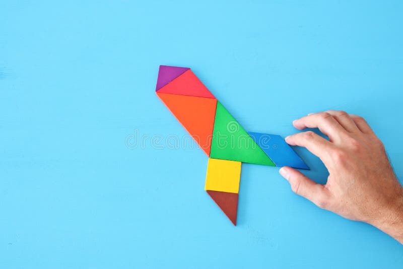 Rocket made from tangram puzzle on blue pastel wooden background. stock image