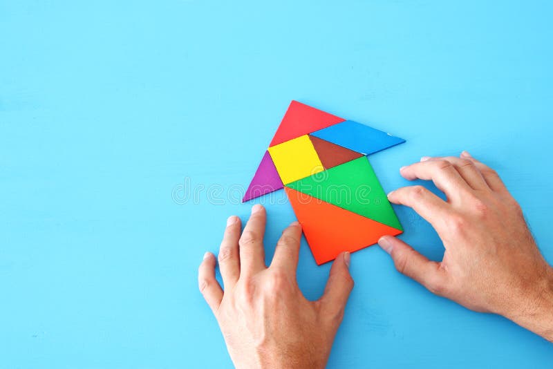 Rocket made from tangram puzzle on blue pastel wooden background. stock image