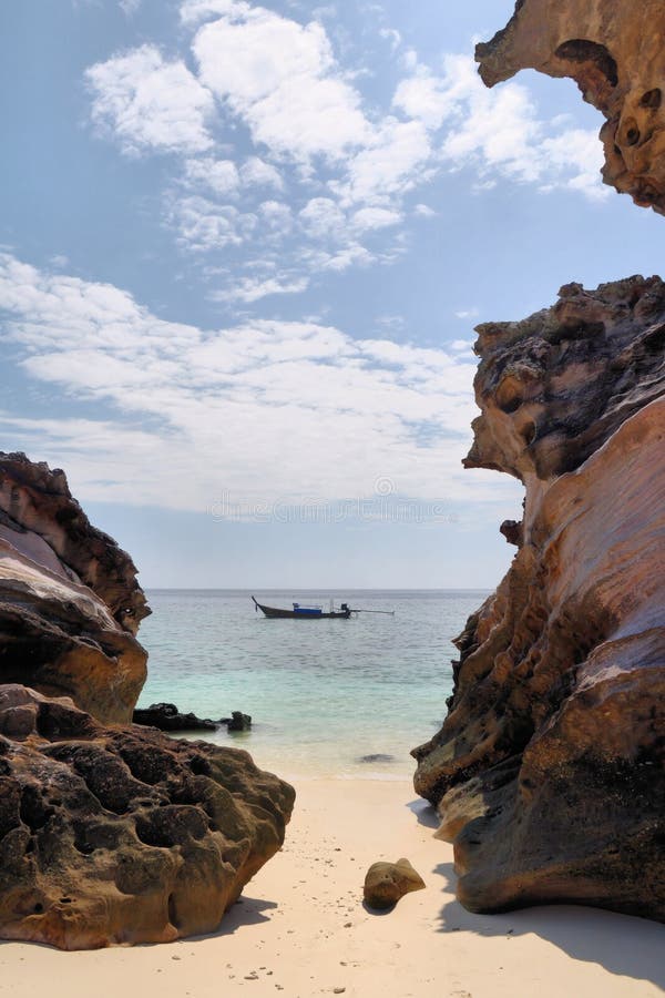 Rocks on the beach, boat on the sea beyond