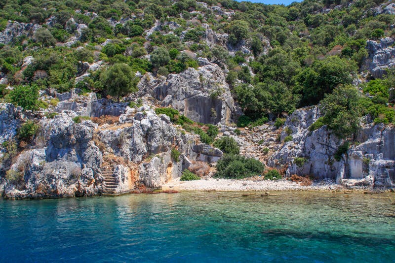 Rocks and bright turquoise water in the Mediterranean Sea. Ruins of an ancient city in Bodrum, Turkey