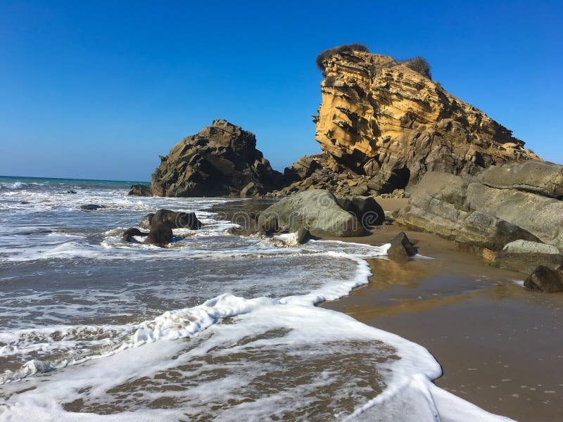 Ondas tirar sobre el El gran roca formación sobre el Playa, cual es un corto caminando abajo línea costera Playa.