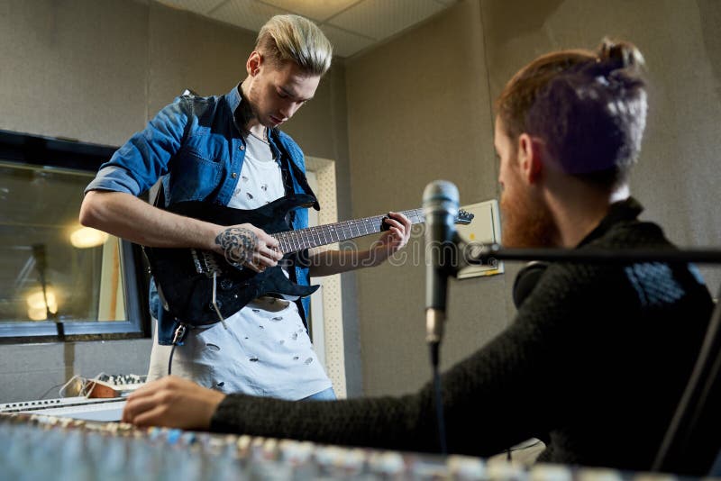 Rockstar gitarzysta komponuje nową piosenkę z producentem obraz stock Rockstar gitarzysta komponuje nową piosenkę z producentem obraz stock