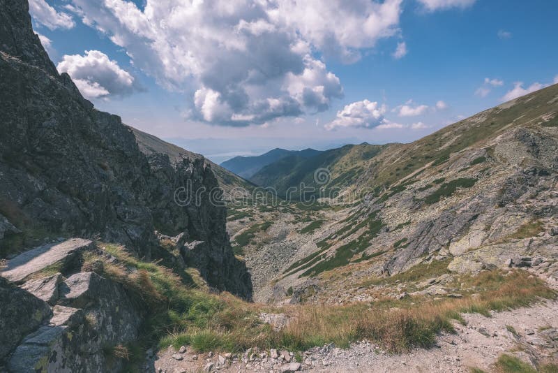 Skalnaté vrcholky hor s turistickými stezkami na podzim ve slovenských Tatrách v západních Karpatech s modrou oblohou a pozdní trávou na kopcích.