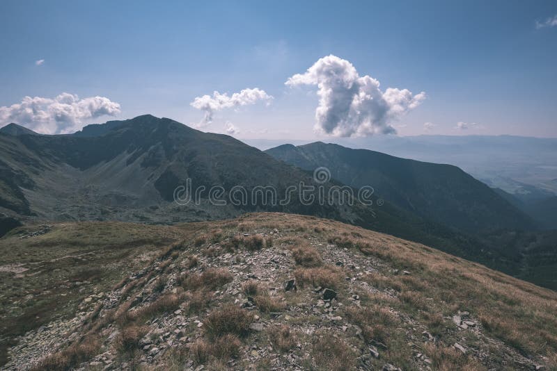 Rocky mountain tops with hiking trails in autumn in Slovakian Tatra western Carpathian with blue sky and late grass on hills.