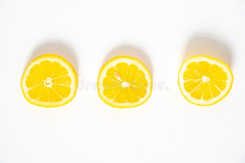 A flat lay of 3 slices of lemon in a row on a plain white background. A flat lay of 3 slices of lemon in a row on a plain white background