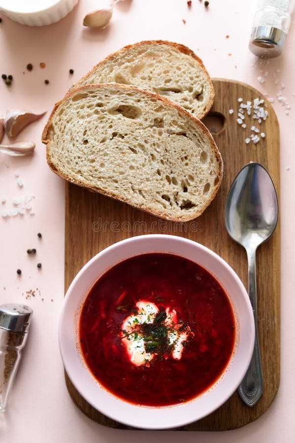 Rode borschtsoep in roze kom met zure room, brood, knoflook en kruiden op roze achtergrond Hoogste mening Vlak leg stock foto Rode borschtsoep in roze kom met zure room, brood, knoflook en kruiden op roze achtergrond Hoogste mening Vlak leg stock foto