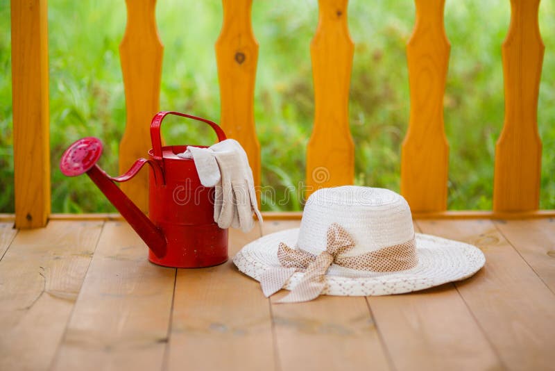 Rode gieter, tuinhandschoenen en strohoed royalty-vrije stock fotografie Rode gieter, tuinhandschoenen en strohoed royalty-vrije stock fotografie