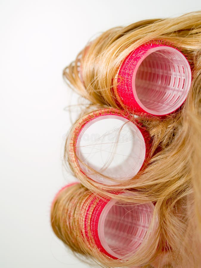 A close-up of red curlers in blond hair. A close-up of red curlers in blond hair