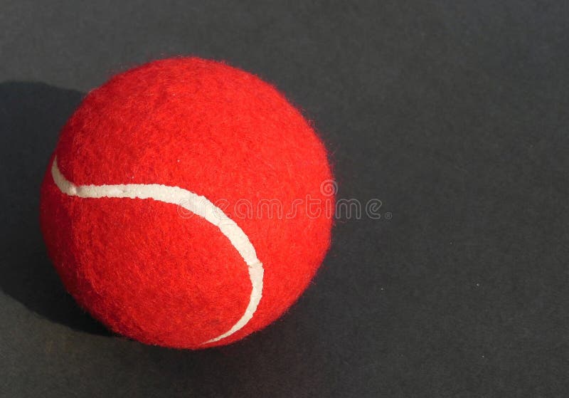 Rode Tennisbal met witte krommelijn op donkere grijze achtergrond royalty-vrije stock afbeelding Rode Tennisbal met witte krommelijn op donkere grijze achtergrond royalty-vrije stock afbeelding