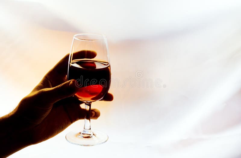 Backlighting red wine glass in a hand. Backlighting red wine glass in a hand