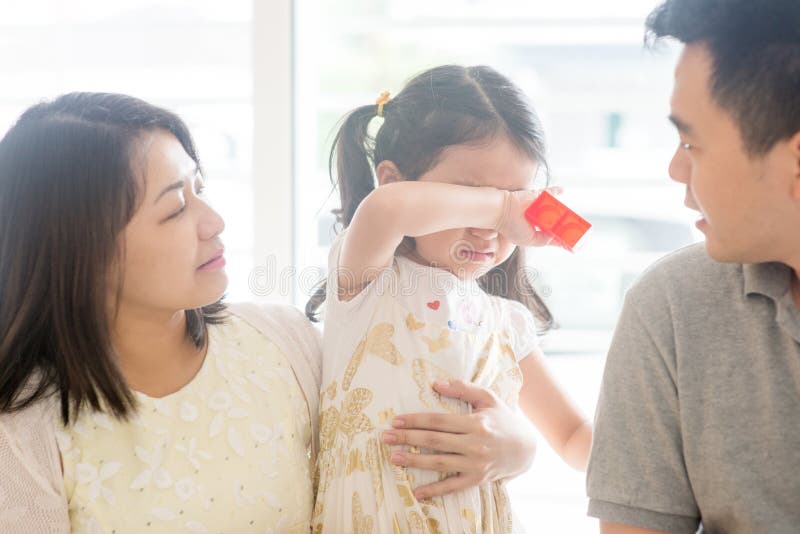 Parents comforting crying daughter. Asian family at home, natural living lifestyle indoors. Parents comforting crying daughter. Asian family at home, natural living lifestyle indoors.