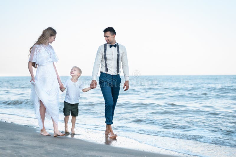 Rodzice trzymający się za ręce syna i chodzący na plaży Piękna para z dzieckiem na morzu fotografia stock Rodzice trzymający się za ręce syna i chodzący na plaży Piękna para z dzieckiem na morzu fotografia stock